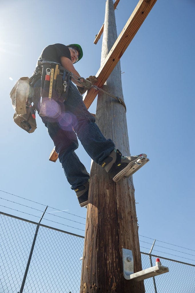 Lineman on pole using lineman tools